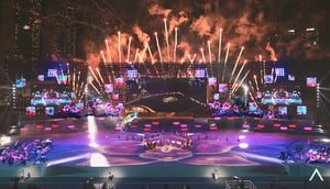 Large stadium filled with performers and fireworks in the background